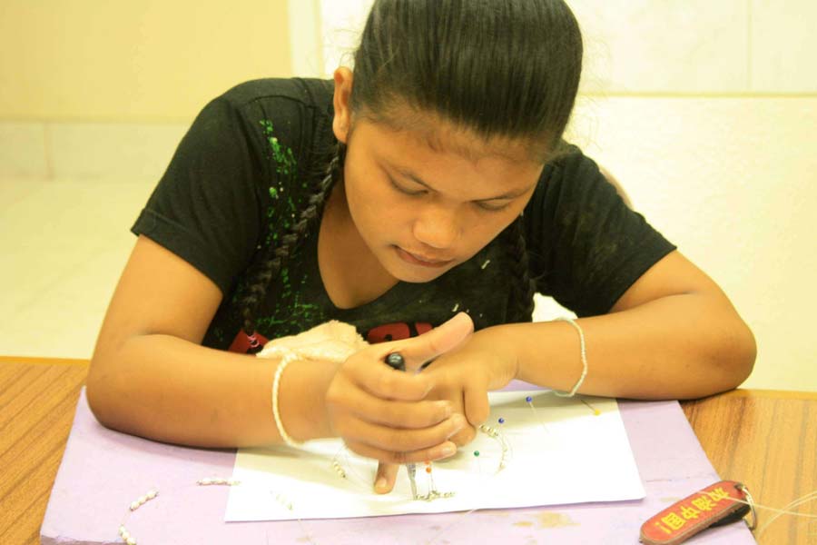 Philippian girl making jewelry for baptism